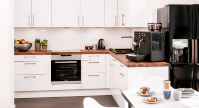 A beautiful office kitchen in white with a wooden worktop