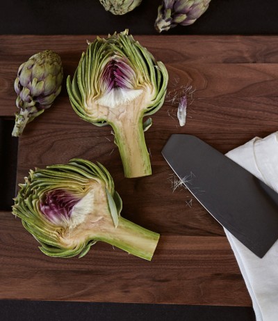 A dark cutting board with an halved artichoke