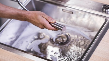 A stainless steel sink is rinsed with water