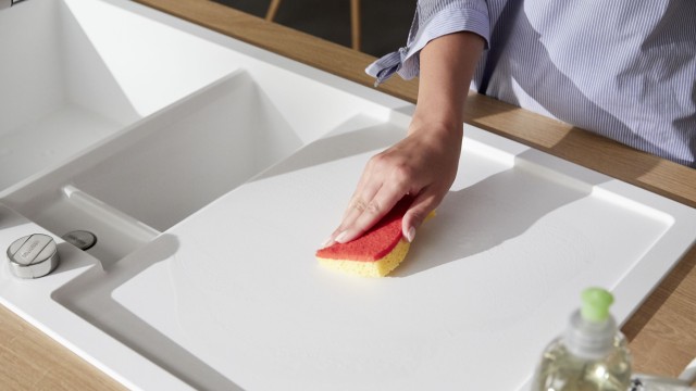 A Silgranit sink is cleaned with a sponge