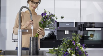 a woman is arranging flowers in a BLANCO stainless steel sink