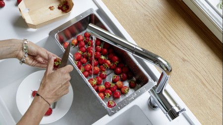 a woman cuts strawberries over a BLANCO sink