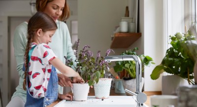 a girl and a woman are repotting a plant on a white silgranit sink