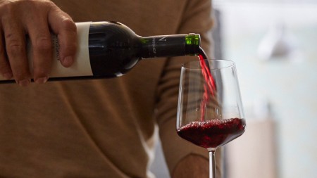 Ein Mann schenkt Rotwein in ein langstieliges Rotweinglas