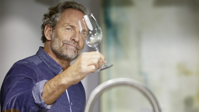 Ein Mann schaut durch ein gereinigtes Weinglas