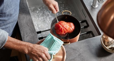 A man is blanching a tomato
