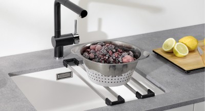 Frozen berries in a stainless steel bowl on a Blanco sink